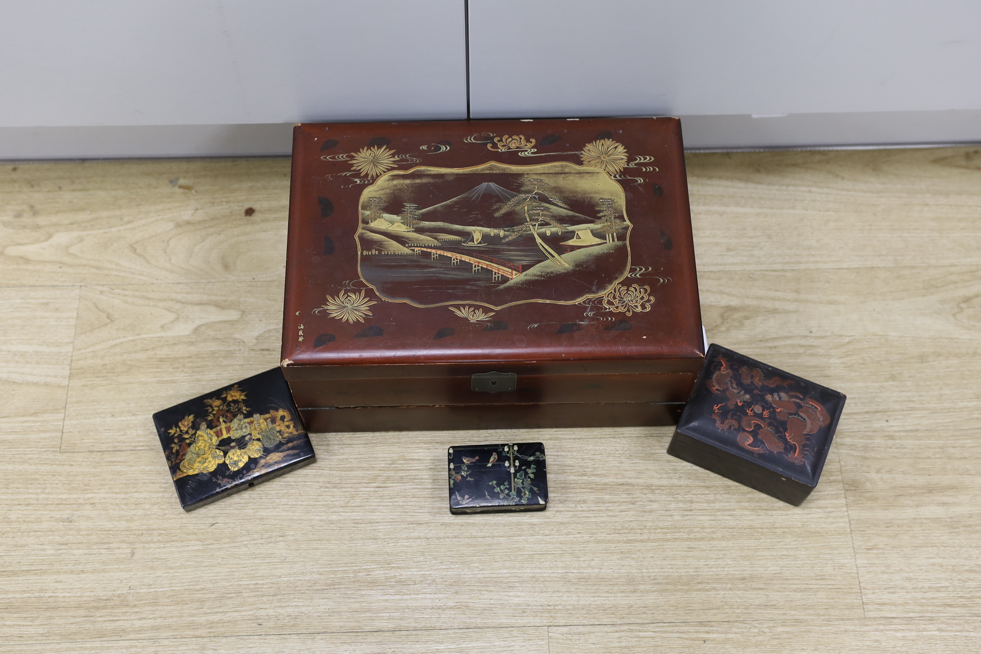 A Japanese lacquer writing box and three black lacquer or papier mache boxes